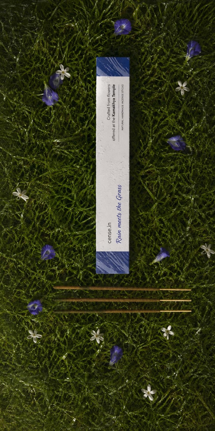 Rain Meets the Grass incense box and sticks on rain-wet grass with butterfly pea and jasmine flowers